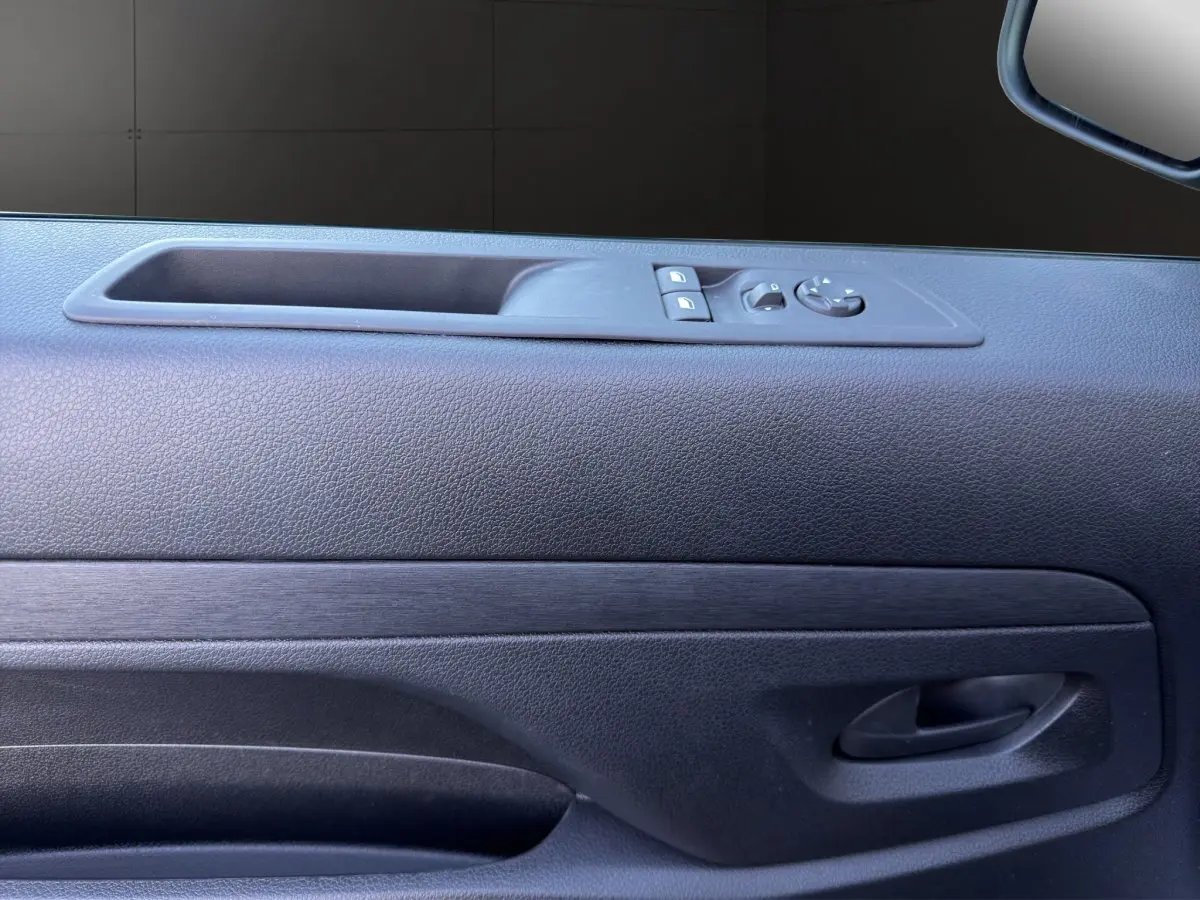 Gros plan sur la porte côté conducteur du Citroën Jumpy noir, avec commandes de vitres et rétroviseur électrique.