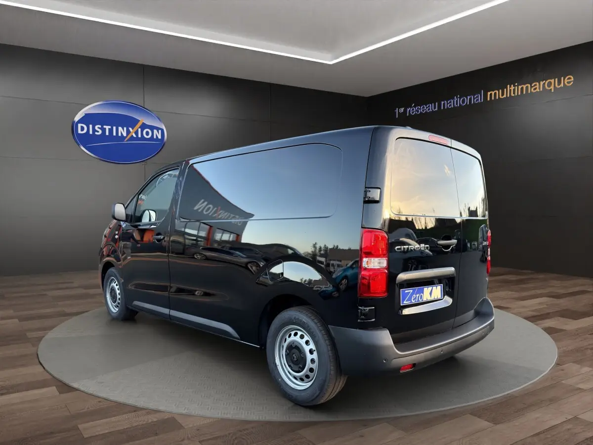 Vue 3/4 arrière droite d’un Citroën Jumpy noir avec hayon fermé, roues acier et logo visible sur fond showroom.