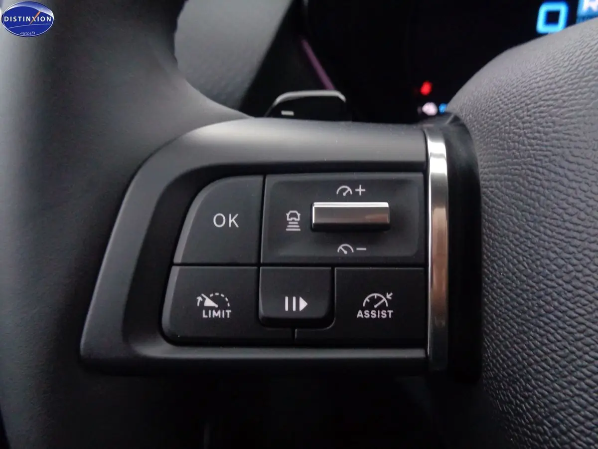 Gros plan sur les commandes au volant côté gauche de la Citroën C5 X noire hybride, avec boutons de régulateur et limiteur de vitesse.