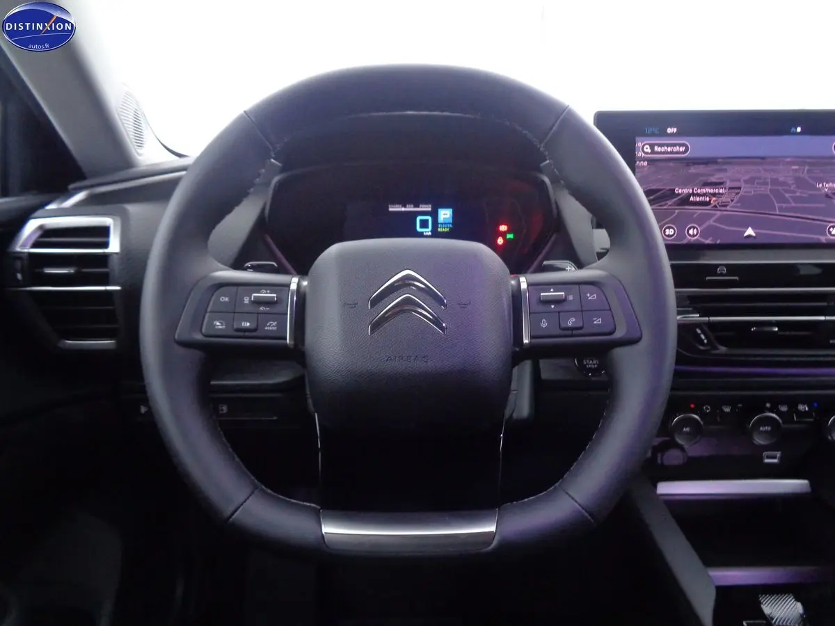 Vue centrée sur le volant cuir noir du Citroën C5 X 1.6 Hybrid 225, avec tableau de bord numérique et écran GPS.