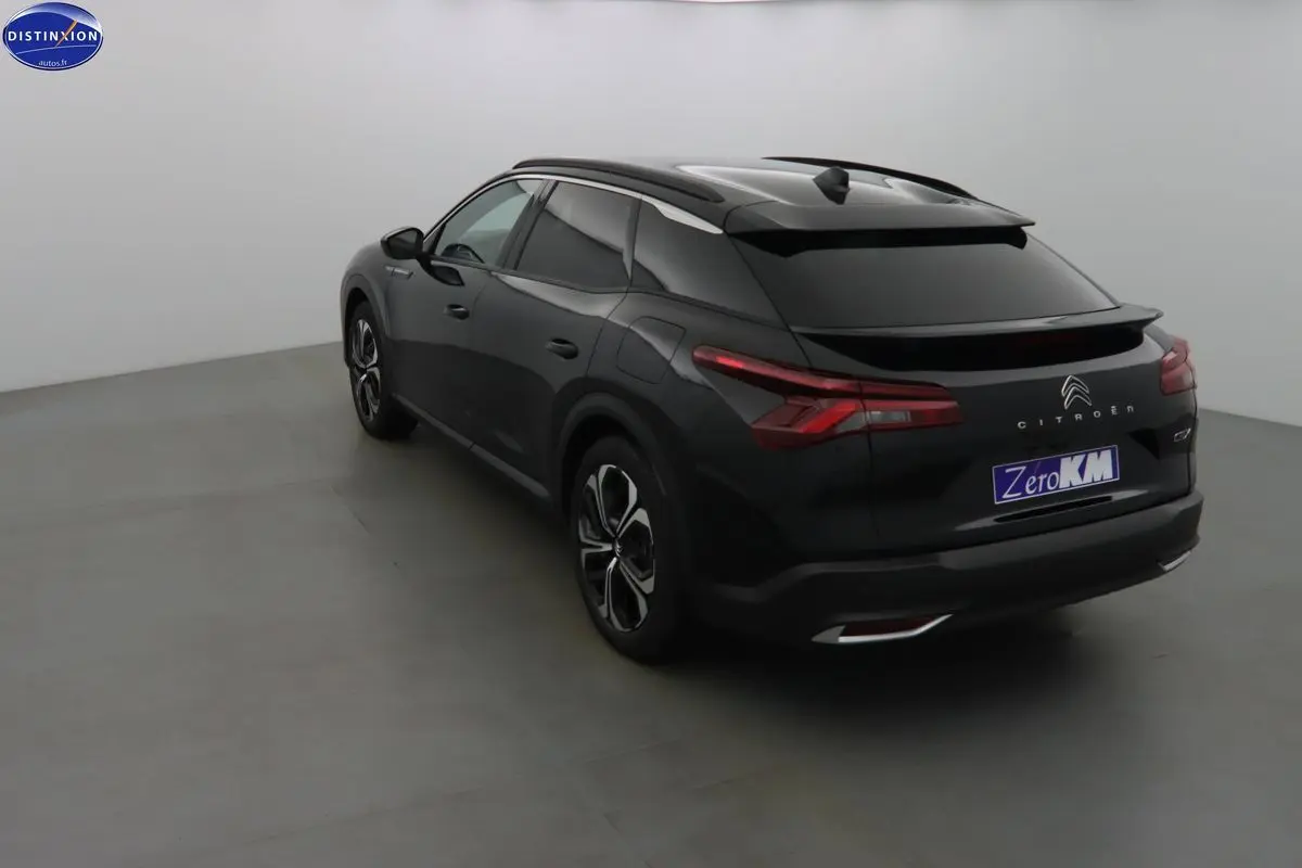 Vue 3/4 arrière droite d'une Citroën C5 X noire métal avec feux arrière LED et jantes bi-ton.