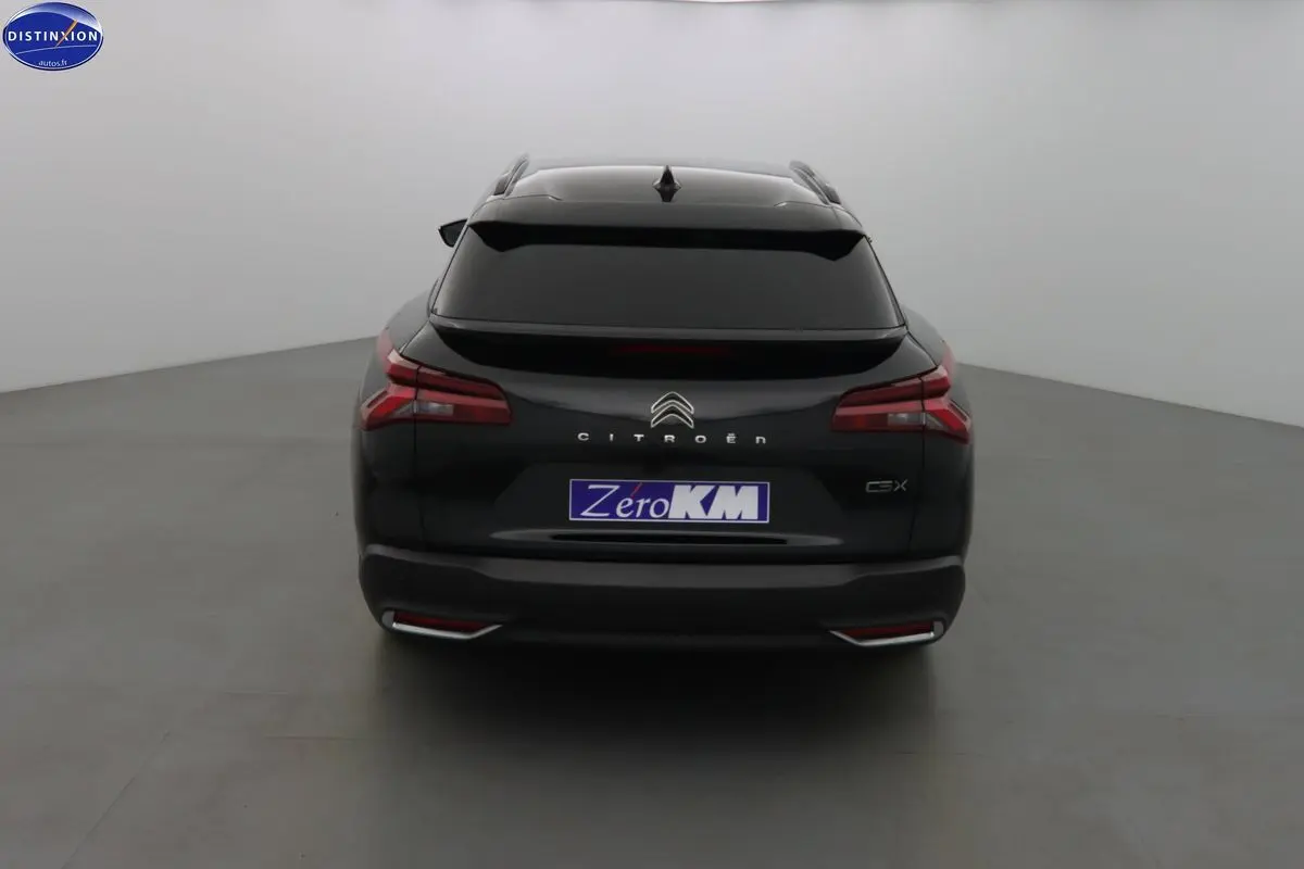 Vue arrière d'une Citroën C5 X noire métal avec feux LED et vitrage arrière teinté dans un studio neutre.
