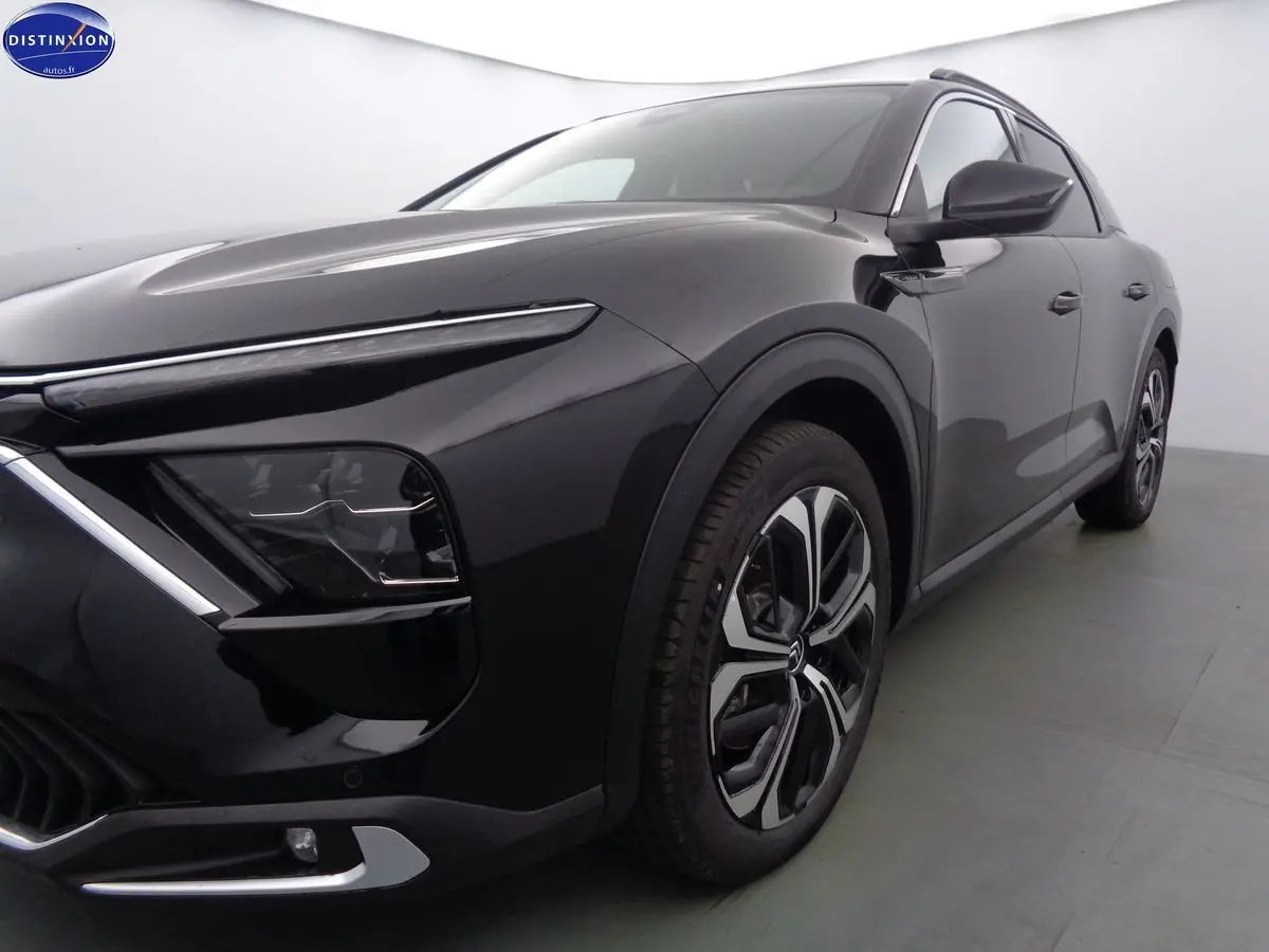 Vue 3/4 avant droit d'une Citroën C5 X noire métal avec phares LED et jantes bi-ton distinctives.