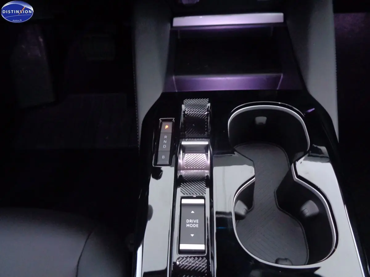 Gros plan sur la console centrale noire brillante de la Citroën C5 X hybride rechargeable avec sélecteur de mode de conduite.