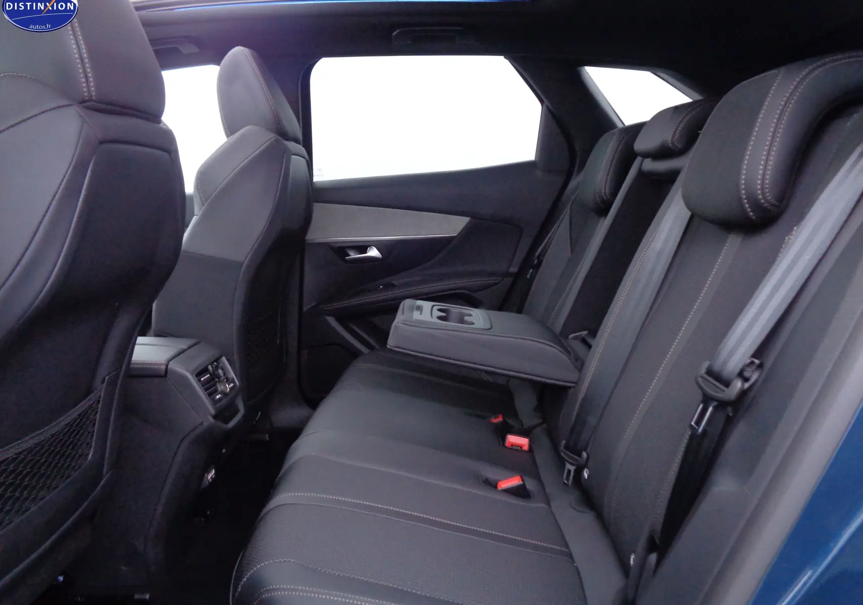 Vue latérale intérieure arrière du Peugeot 3008 bleu Celebes Metal avec sièges noirs en cuir et accoudoir central déployé.