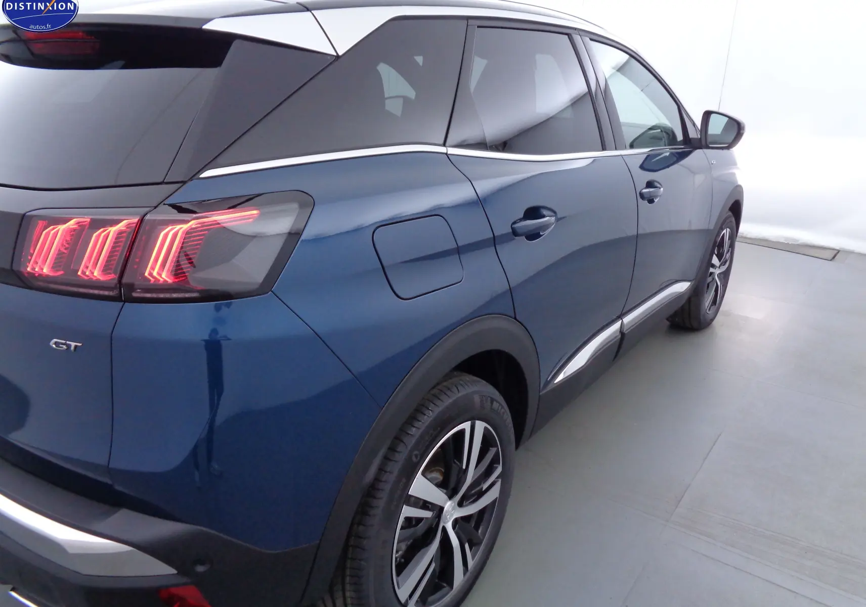 Vue 3/4 arrière droite d'un Peugeot 3008 GT bleu Célèbes Métal avec feux arrière LED distinctifs et jantes alliage bicolores.