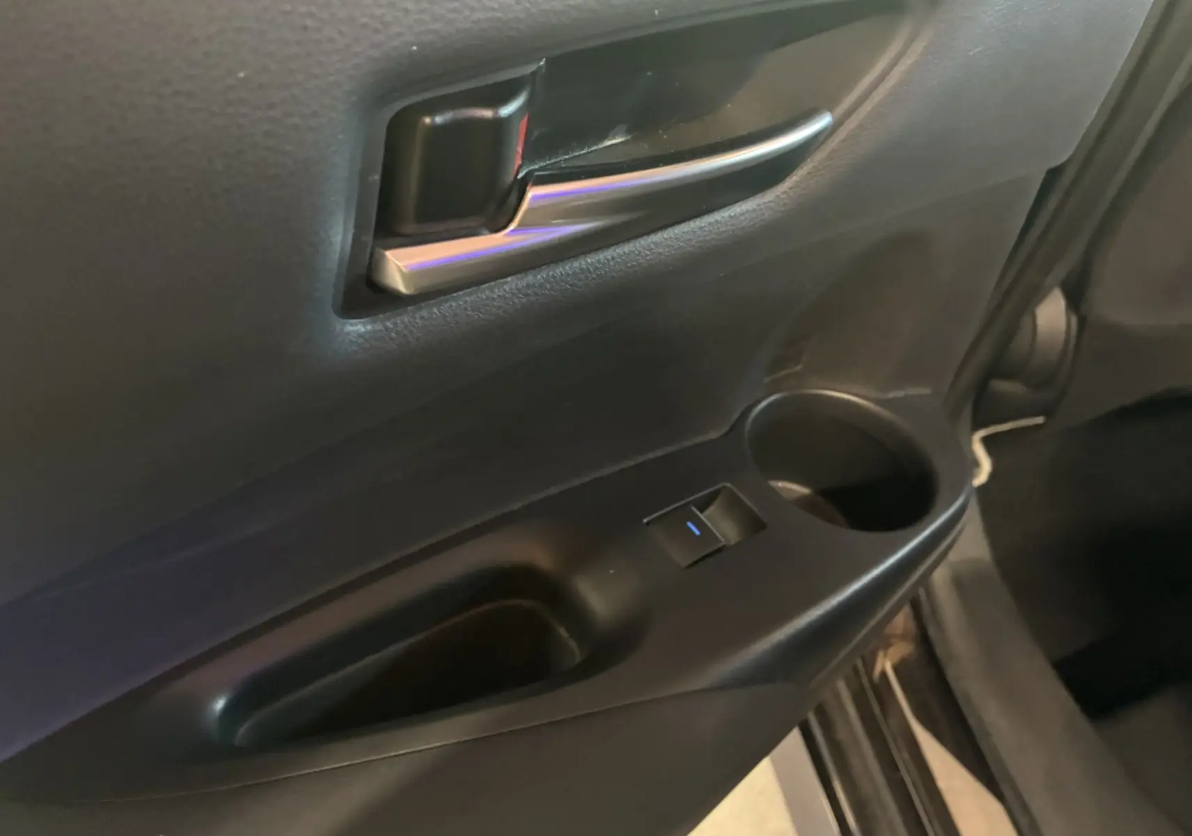 Gros plan sur la poignée intérieure et le panneau de porte côté conducteur d'une Toyota Corolla noire 2020.