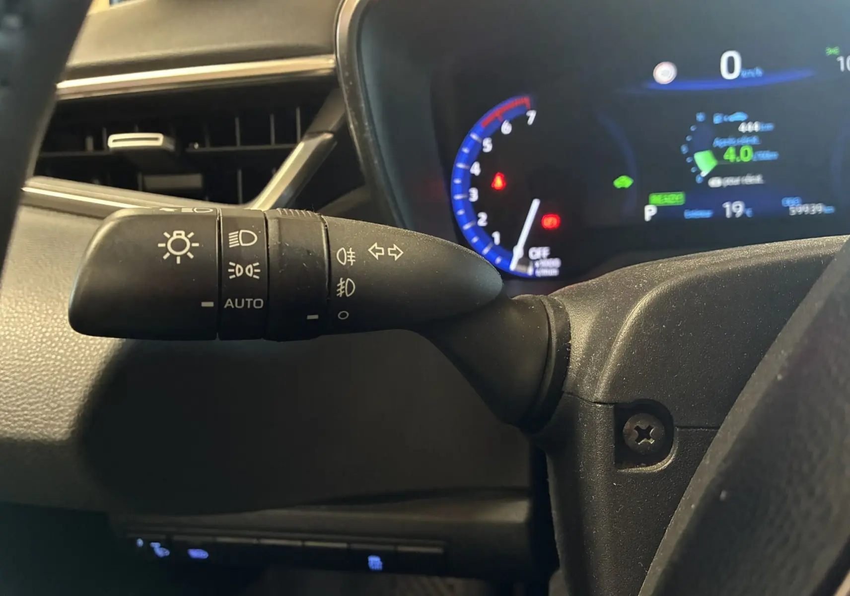 Gros plan sur la commande des phares et clignotants à gauche du volant dans le tableau de bord noir de la Toyota Corolla hybride 2020.