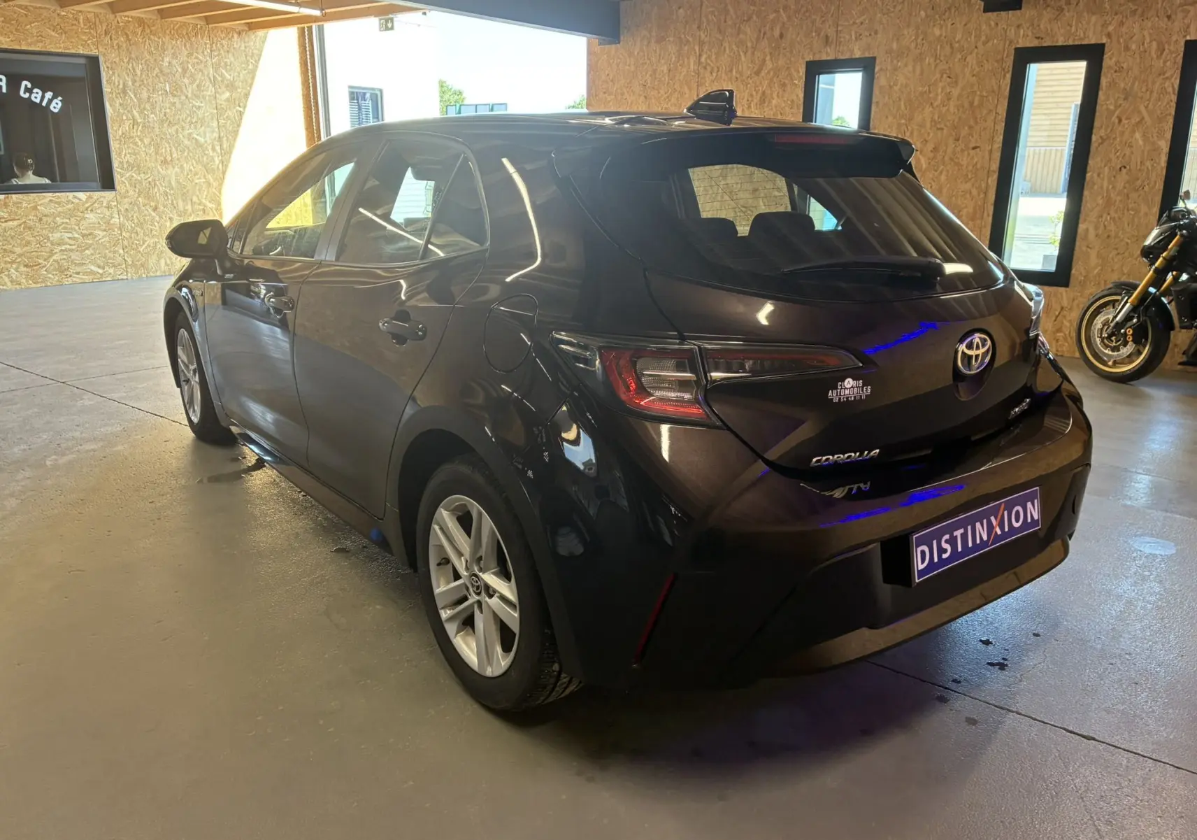 Toyota Corolla 1.8 122 Dynamic noire vue 3/4 arrière droit en intérieur avec jantes alu et feux LED distinctifs.