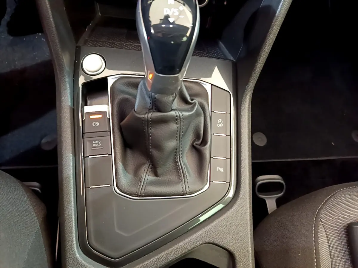 Gros plan sur la console centrale du Volkswagen Tiguan gris clair, mettant en valeur le levier de vitesse automatique et les boutons de contrôle.