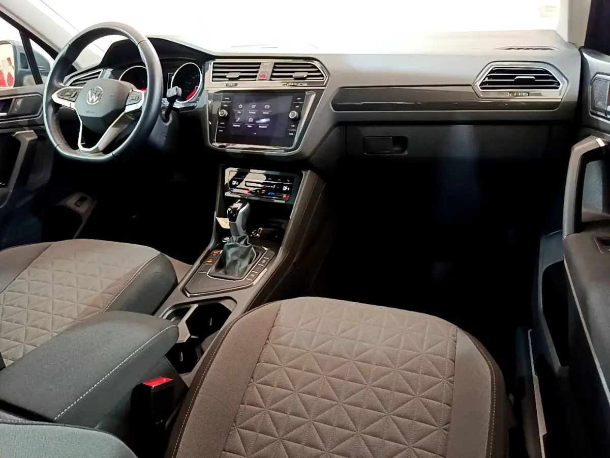 Vue intérieure avant du Volkswagen Tiguan 2.0 TDI 2021, montrant le tableau de bord et les sièges gris avec console centrale.