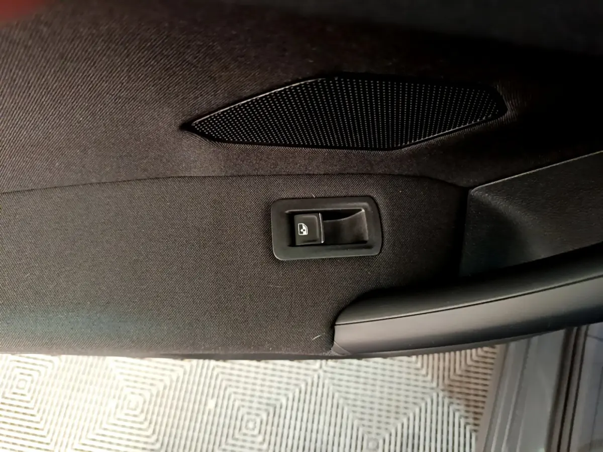Détail de la commande de lève-vitre sur la porte intérieure noire côté conducteur du Volkswagen Tiguan gris clair.