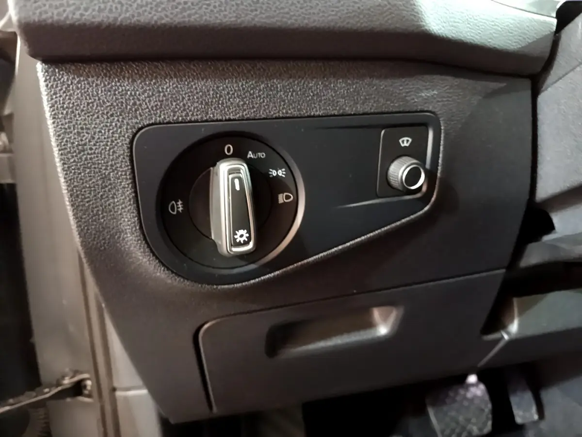 Gros plan sur le panneau de commande des phares noir à gauche du volant dans un Volkswagen Tiguan gris clair 2021.