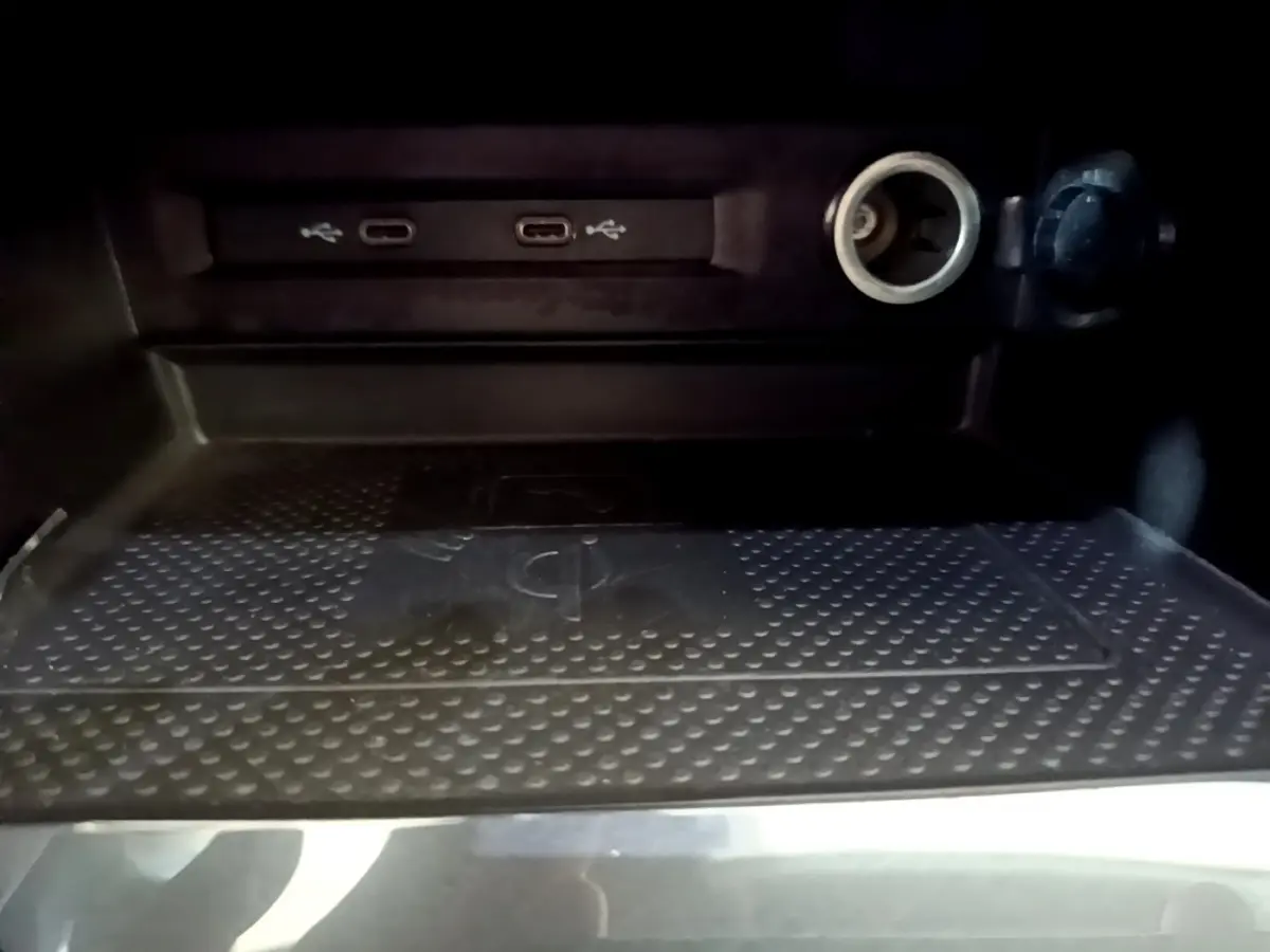 Gros plan sur la zone de recharge sans fil et ports USB-C du Volkswagen Tiguan gris clair, intérieur sombre.