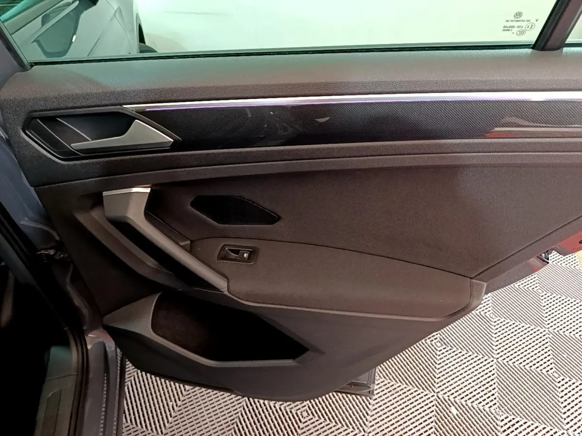 Vue intérieure côté gauche de la porte avant grise du Volkswagen Tiguan 2021 avec poignée argentée et garniture noire.