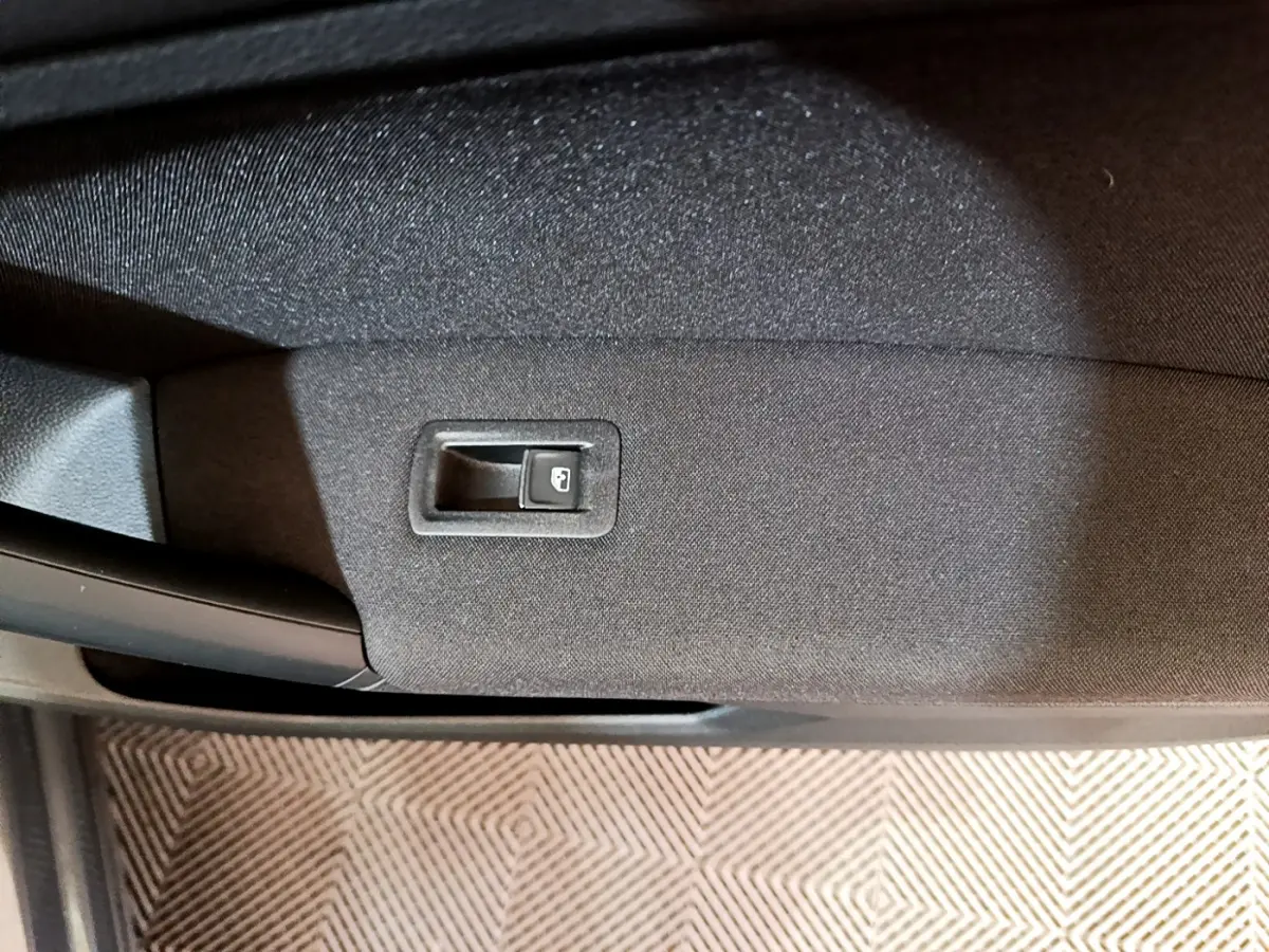 Gros plan sur la poignée intérieure de porte arrière droite du Volkswagen Tiguan gris clair, tissu noir.