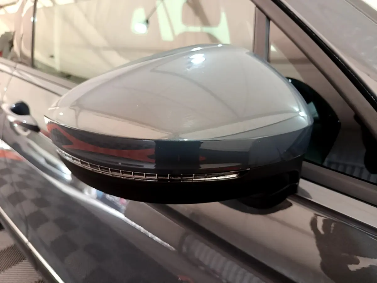 Gros plan sur le rétroviseur droit gris clair du Volkswagen Tiguan 2021 avec clignotant intégré visible.