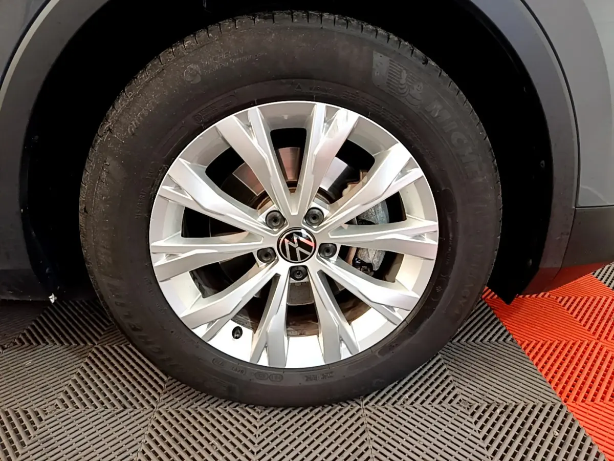 Gros plan sur la roue avant droite du Volkswagen Tiguan gris clair avec jante alliage à rayons multiples.
