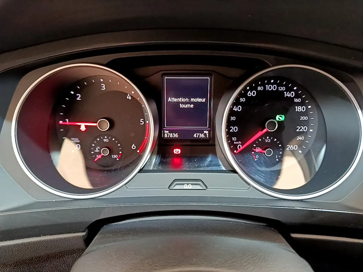 Vue rapprochée du tableau de bord du Volkswagen Tiguan gris clair, affichant les compteurs et un message moteur allumé.