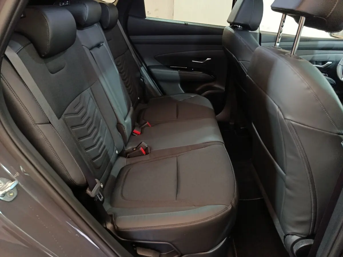 Vue intérieure côté gauche des sièges arrière noirs du Hyundai Tucson 2025, avec appuie-têtes et ceintures visibles.