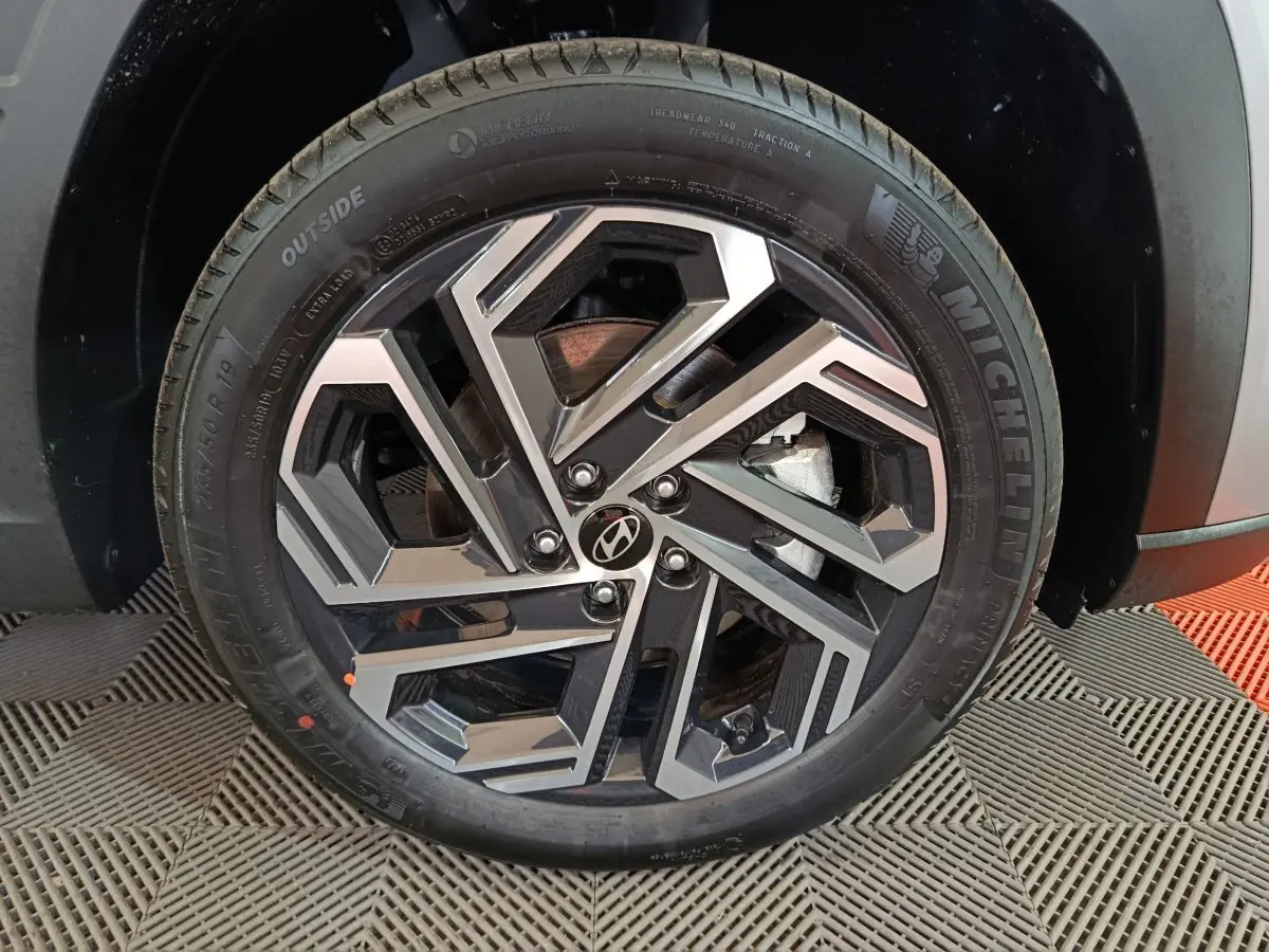 Gros plan sur la roue avant droite du Hyundai Tucson gris clair 2025 avec jante alliage au design géométrique.
