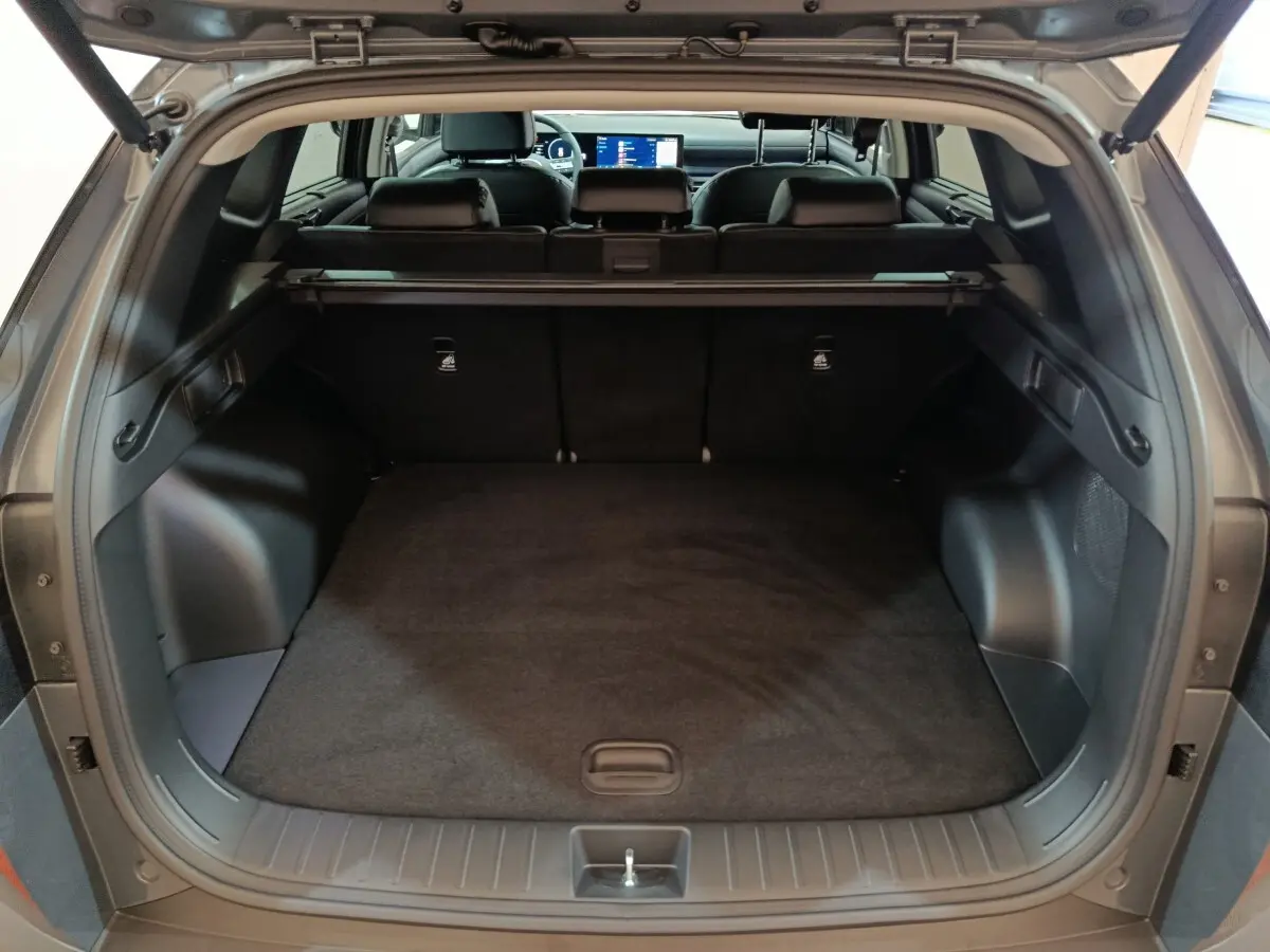 Coffre ouvert du Hyundai Tucson gris clair 2025, vue arrière montrant l’espace de chargement et la banquette arrière.