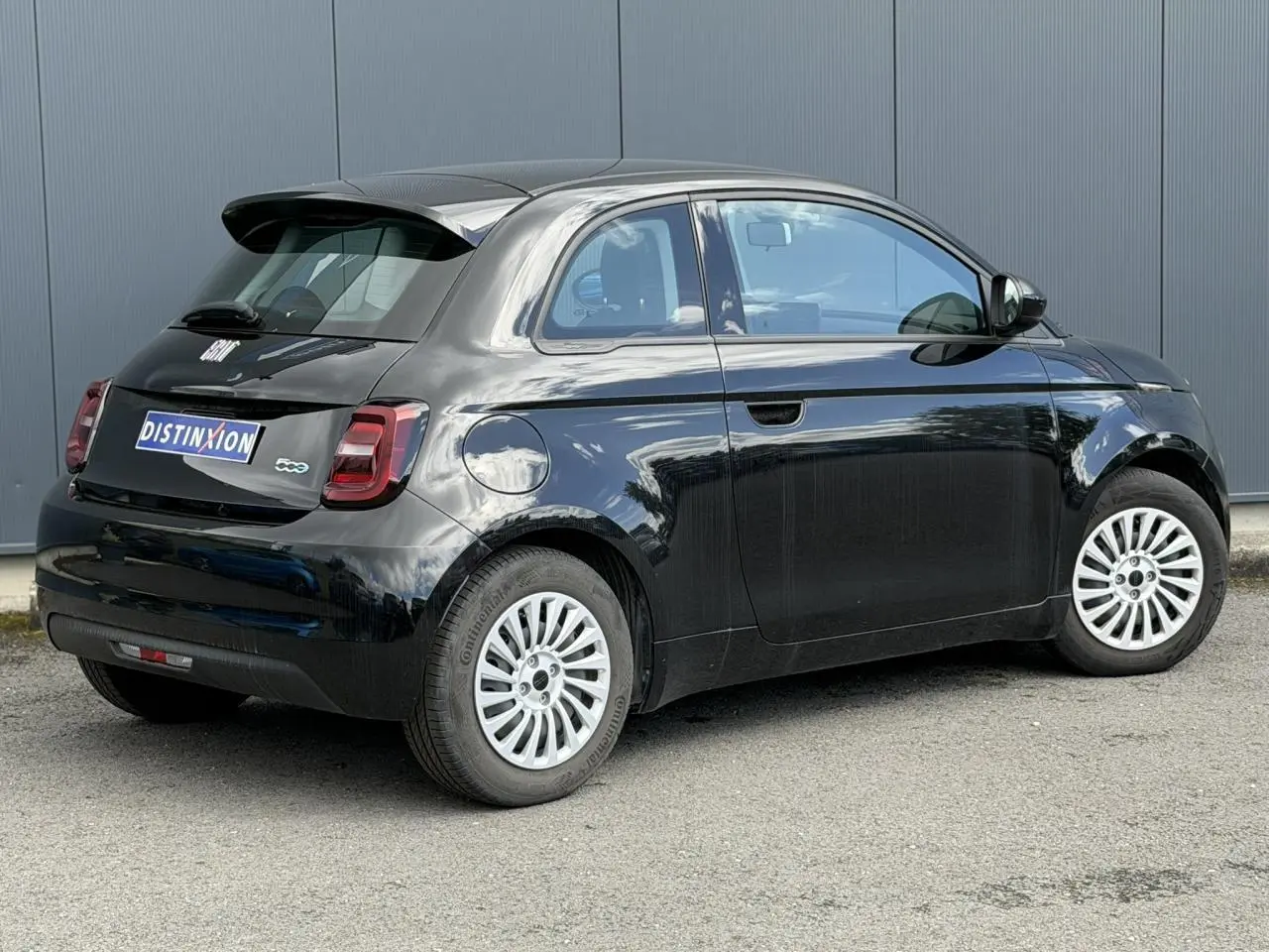 Vue 3/4 arrière droite d'une FIAT 500 électrique 2024 en noir Onyx avec jantes alu 16 pouces et feux arrière LED.