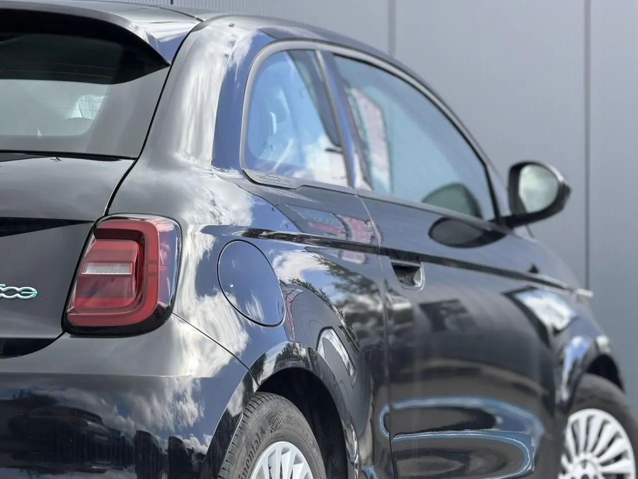 Vue 3/4 arrière droite d'une Fiat 500 électrique 2024 en peinture Noir Onyx avec jantes alu 16 pouces.