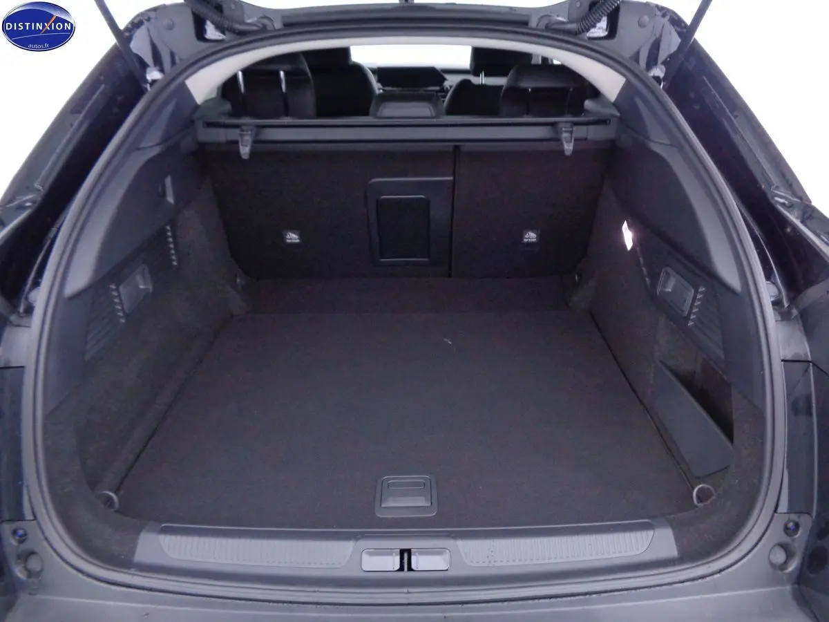 Coffre ouvert vu de l'arrière d'une Citroën C5 X noir métal, montrant un espace de chargement spacieux et bien fini.