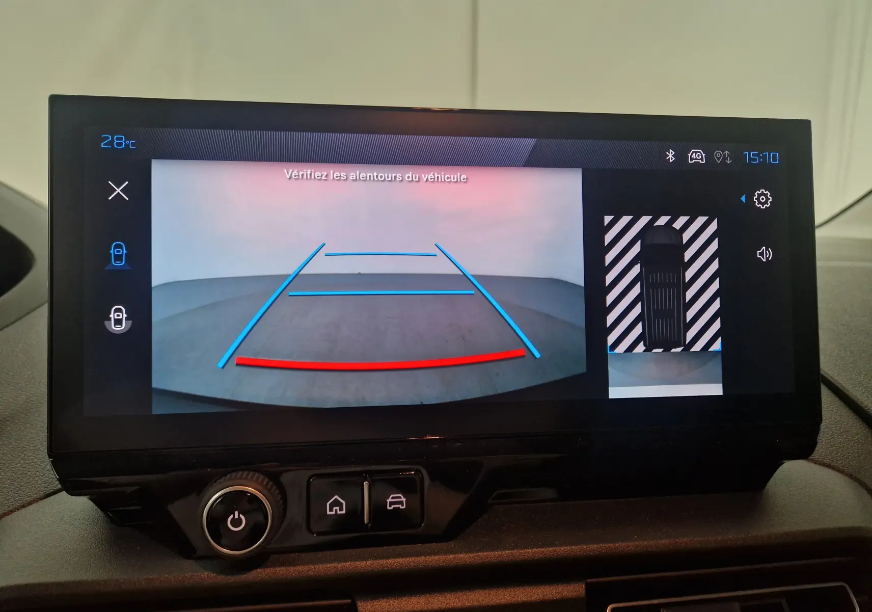 Écran de caméra de recul du Peugeot Partner blanc 2025 affichant les lignes de guidage et la vue aérienne du véhicule.