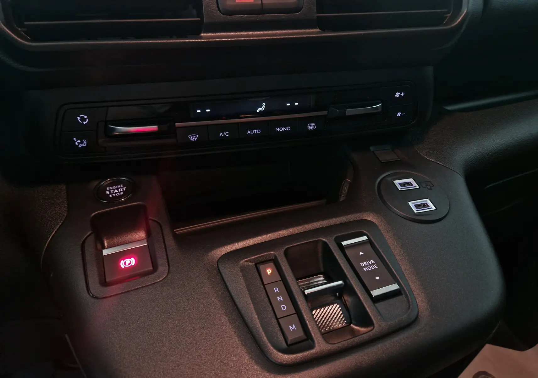 Vue rapprochée de la console centrale du Peugeot Partner blanc 2025, montrant la commande de boîte auto et les commandes climatisation.