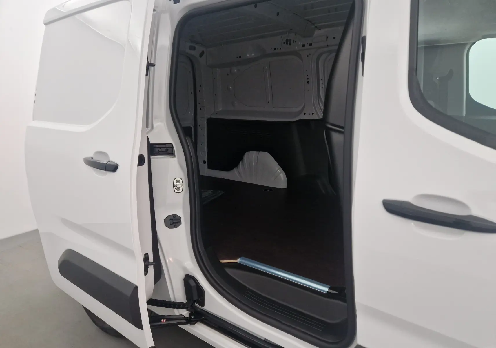 Vue latérale gauche du Peugeot Partner blanc 2025 avec porte coulissante ouverte dévoilant l'espace de chargement vide.