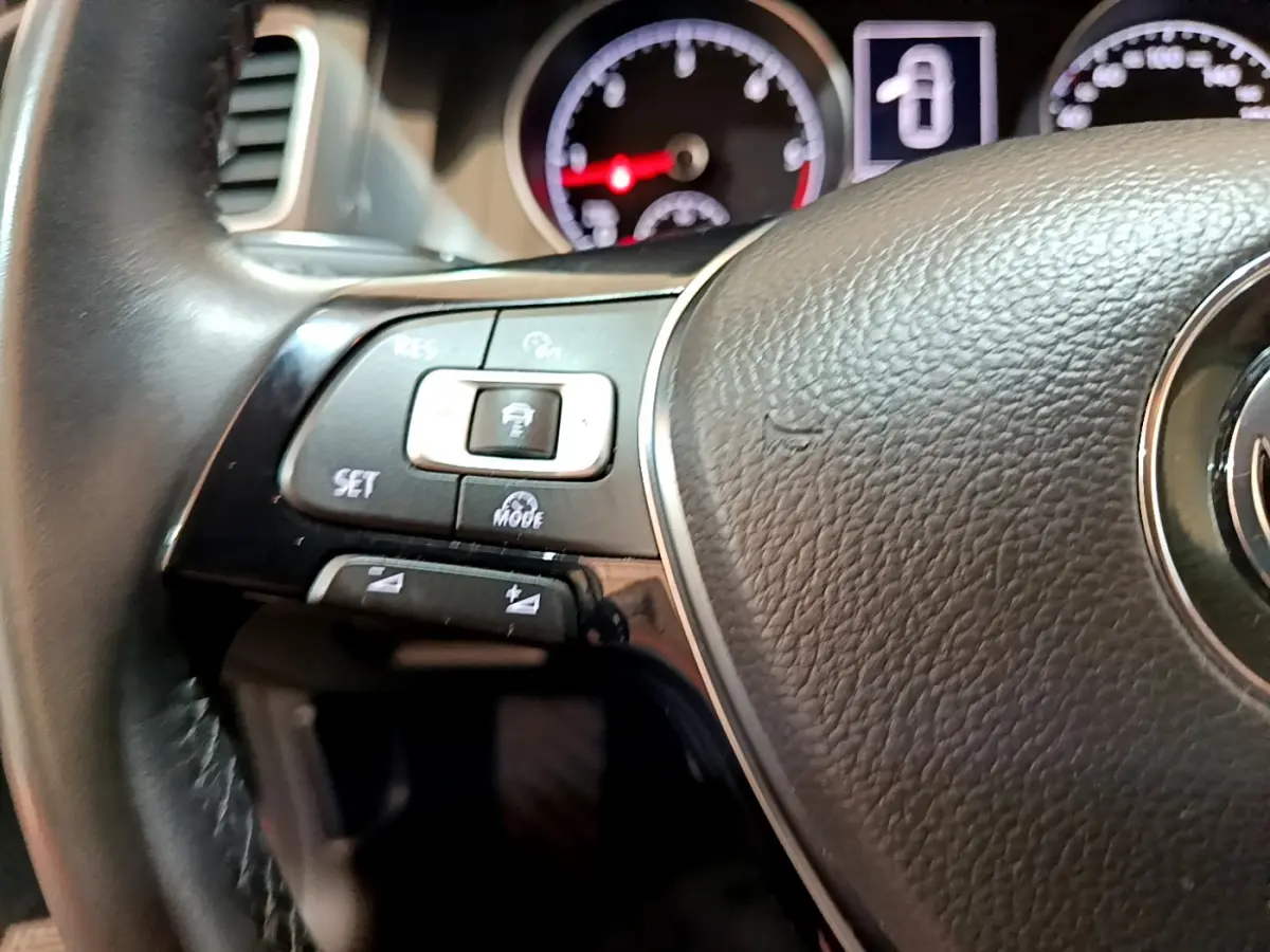 Gros plan sur le volant cuir noir de la Volkswagen Golf 2018, avec commandes multifonctions et tableau de bord en arrière-plan.