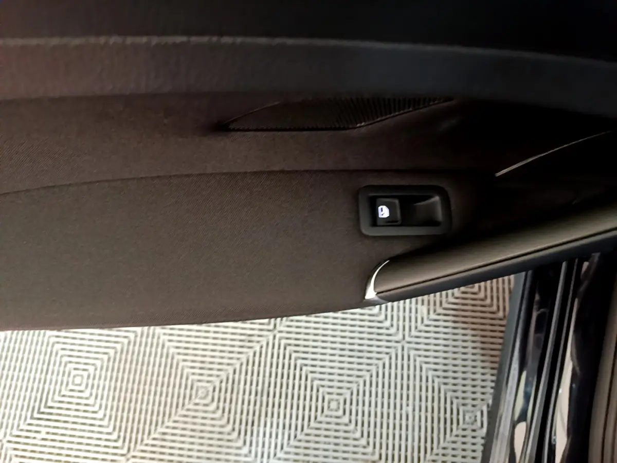 Détail de la poignée intérieure de porte côté conducteur d'une Volkswagen Golf noire, vue en plongée.