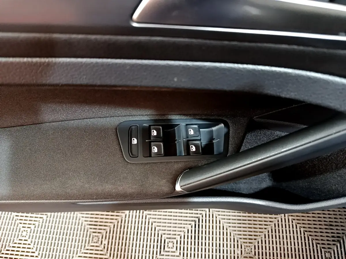 Gros plan sur la commande des vitres électriques côté conducteur d'une Volkswagen Golf noire, intérieur tissu noir.