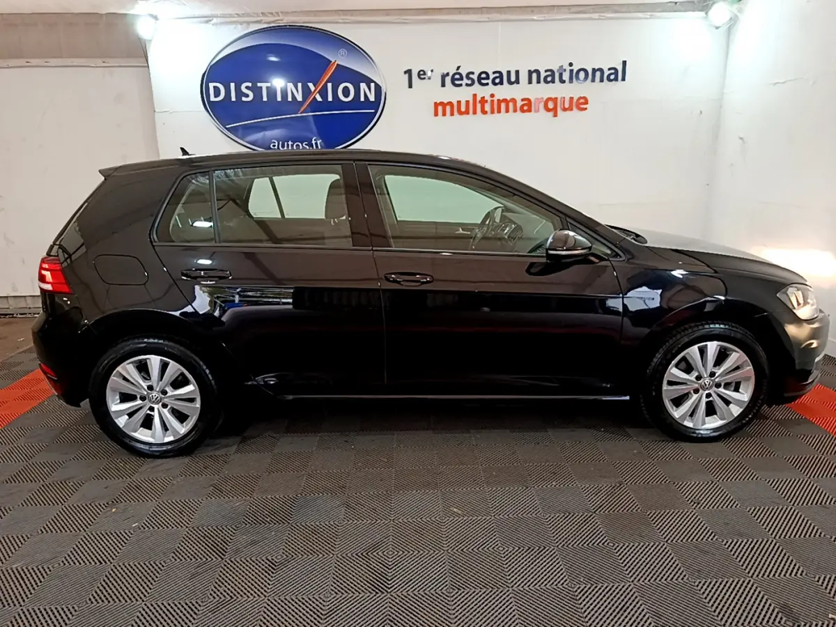 Profil côté gauche d'une Volkswagen Golf noire 2018, finition Confort Business, dans un showroom intérieur.