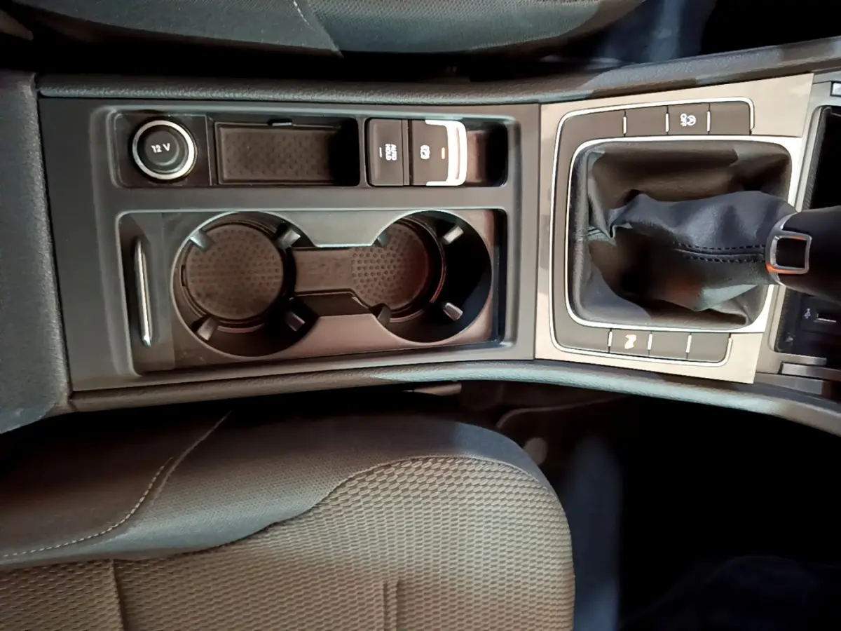 Vue rapprochée de la console centrale noire de la Volkswagen Golf 2018, avec levier de vitesses manuel et porte-gobelets.