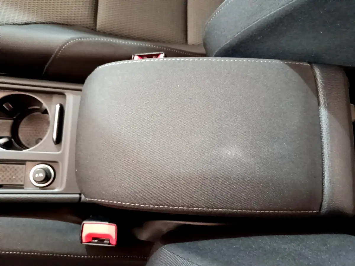 Vue rapprochée de l'accoudoir central noir et des porte-gobelets entre les sièges avant d'une Volkswagen Golf 2018.