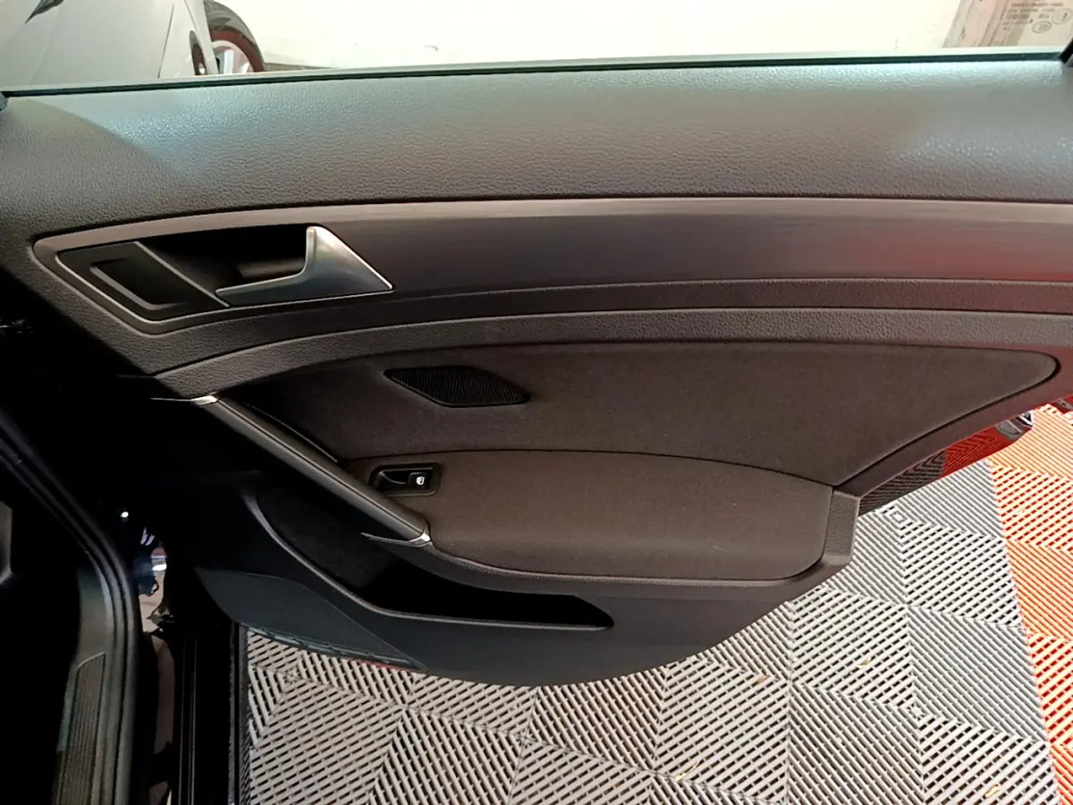 Vue intérieure côté gauche de la porte avant noire d'une Volkswagen Golf 2018 avec poignée argentée et habillage tissu.