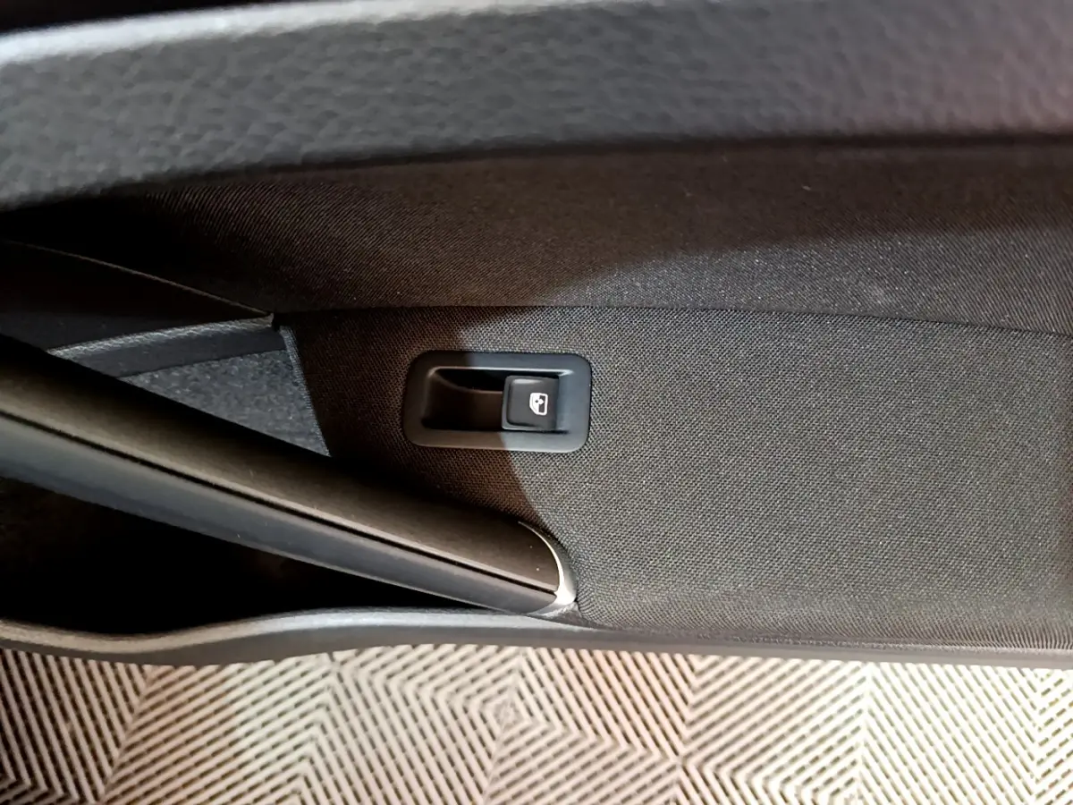 Détail de la commande d'ouverture du coffre sur la garniture intérieure noire d'une Volkswagen Golf 2018.