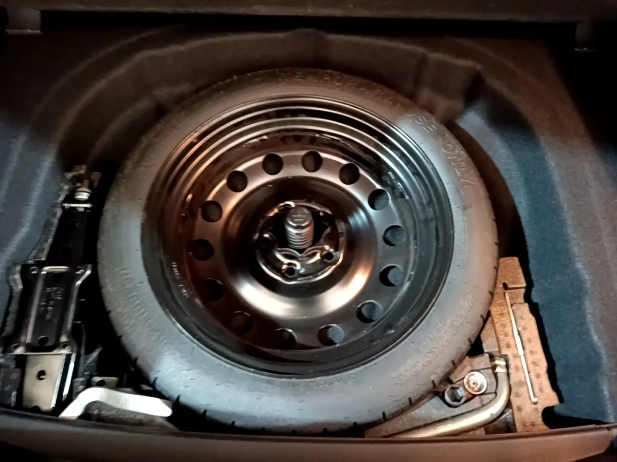 Gros plan sur la roue galette noire de secours dans le coffre d'une Volkswagen Golf noire de 2018.