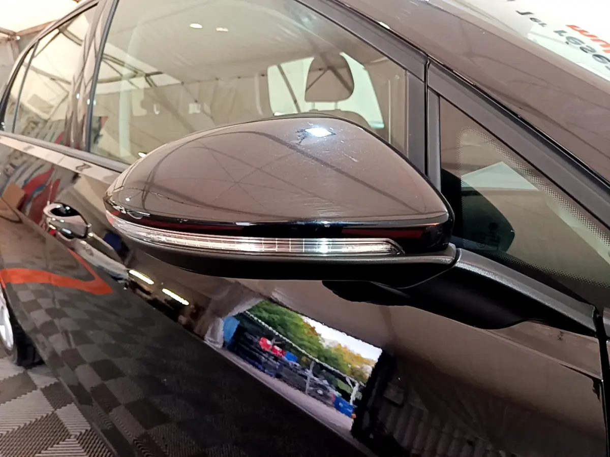 Rétroviseur noir avec clignotant intégré, vue rapprochée côté conducteur de la Volkswagen Golf noire 2018.