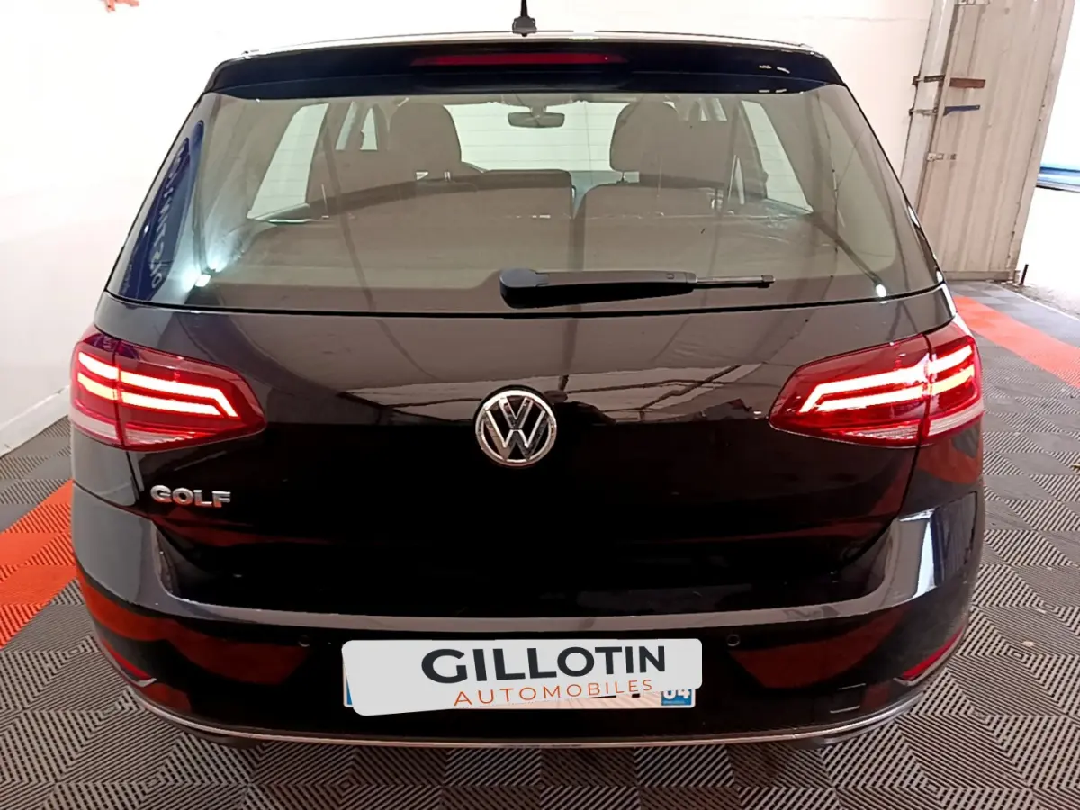 Vue arrière d'une Volkswagen Golf noire de 2018 avec feux LED allumés et logo VW bien visible.