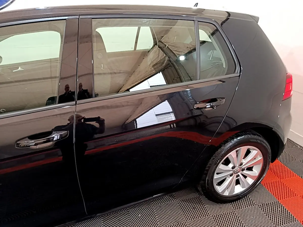 Vue latérale droite d'une Volkswagen Golf noire, mettant en valeur les portes arrière et la roue arrière avec jante argentée.