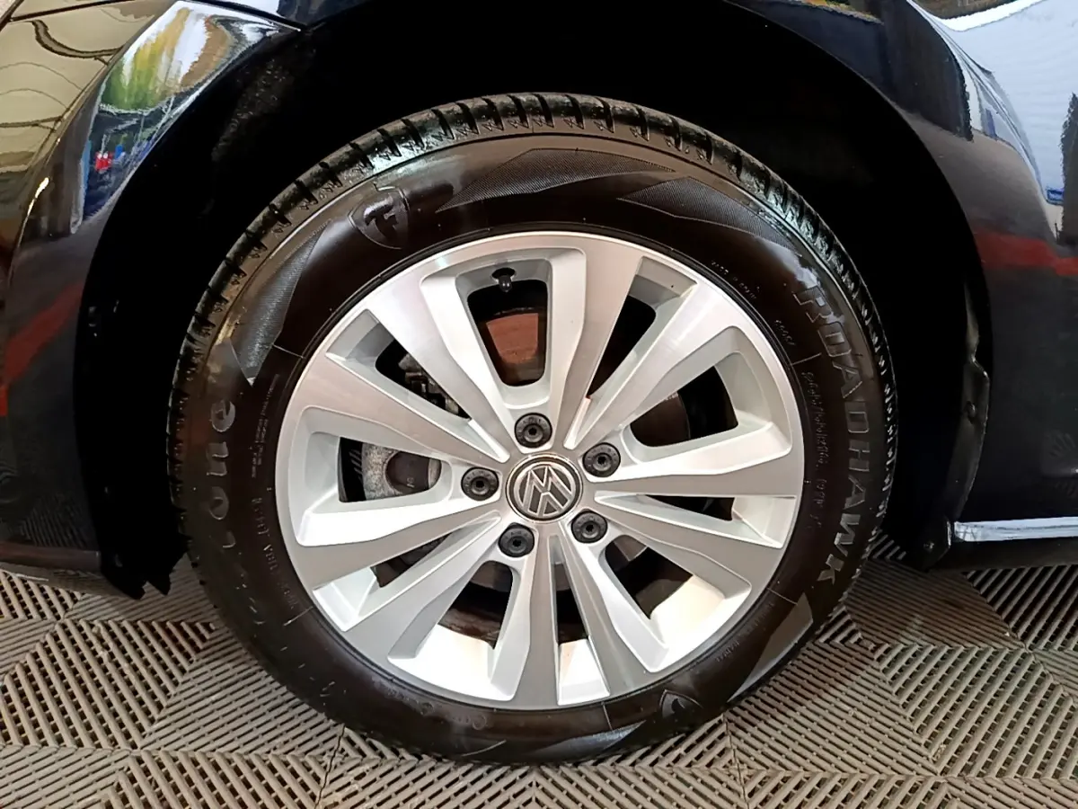 Gros plan sur la roue avant droite d'une Volkswagen Golf noire, jante alliage argentée à 10 branches.