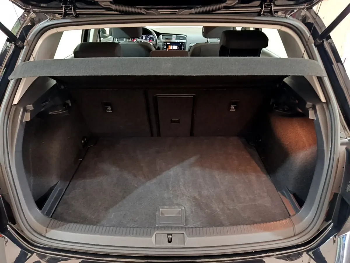 Vue arrière du coffre ouvert d'une Volkswagen Golf noire 2018, montrant l'espace de chargement et la tablette cache-bagages.