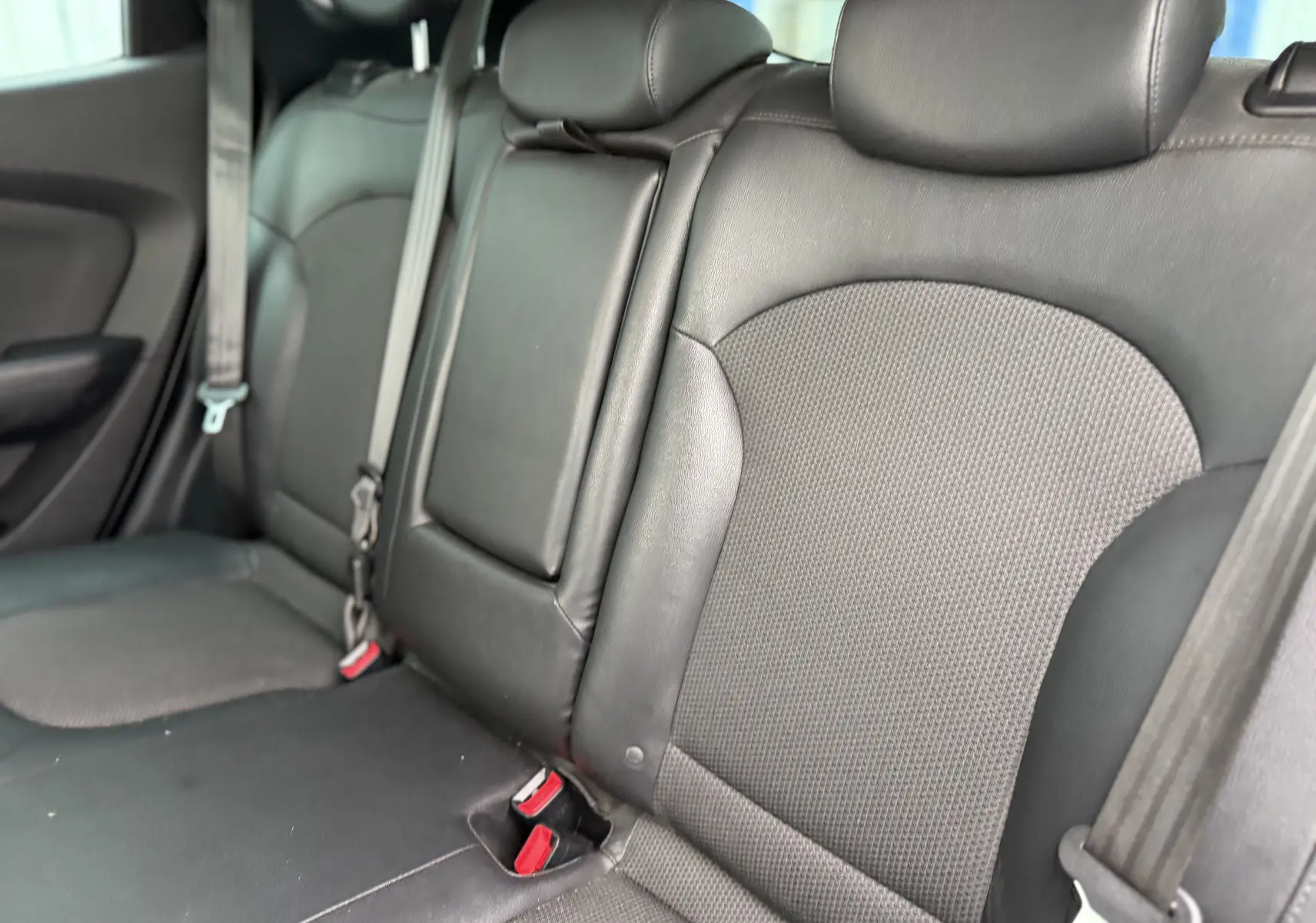 Vue rapprochée des sièges arrière en cuir noir du Hyundai ix35 2014, avec ceintures de sécurité visibles.