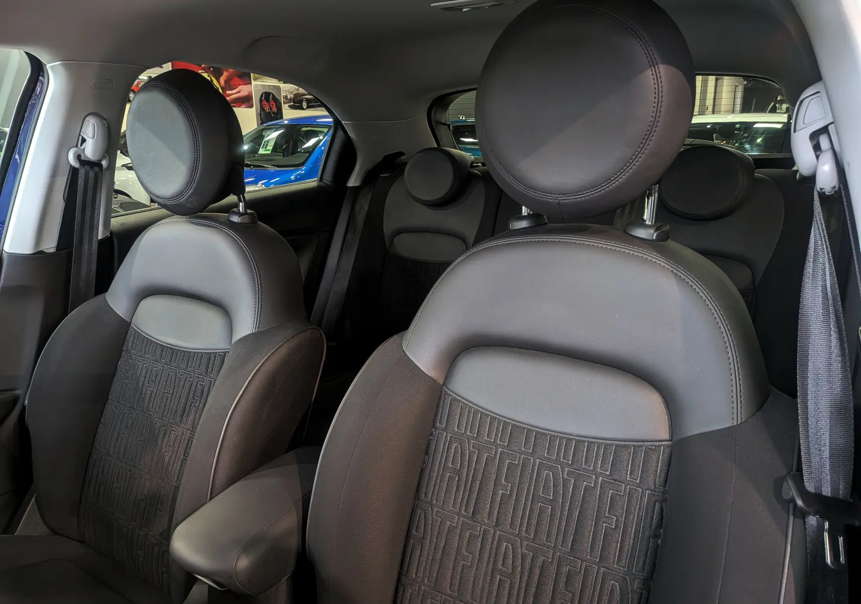 Vue intérieure des sièges avant en cuir noir avec logo FIAT embossé sur les dossiers du FIAT 500X 2024.