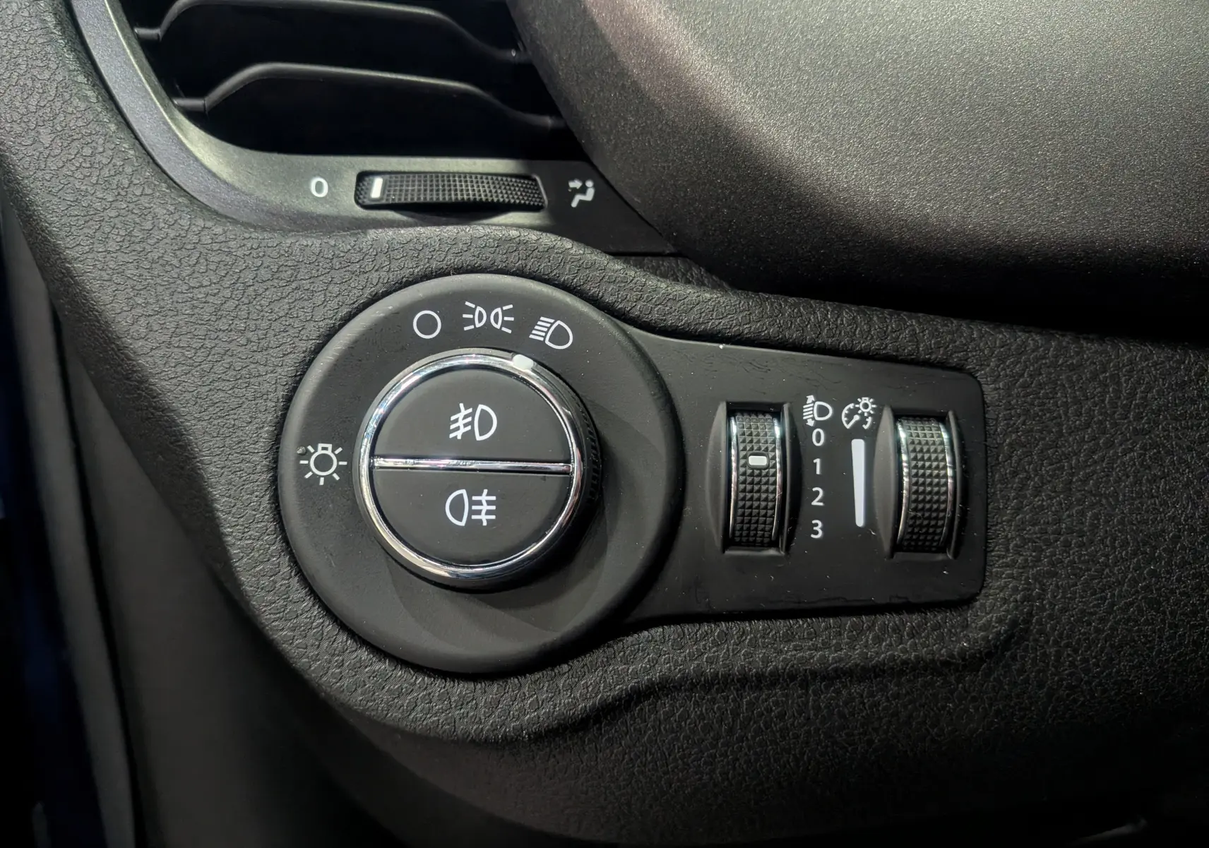 Gros plan sur les commandes d’éclairage du tableau de bord d’une FIAT 500X 2024, finition noire texturée.