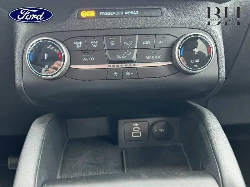 Détail de la console centrale du Ford Kuga 2023, montrant les commandes de climatisation bi-zone et prises USB/12V.